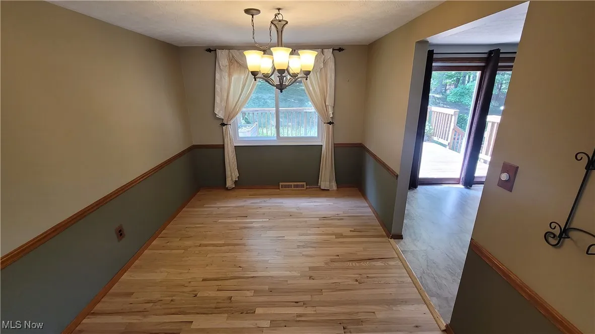 Unfurnished dining area featuring light wood-style floors, a chandelier, and a textured ceiling