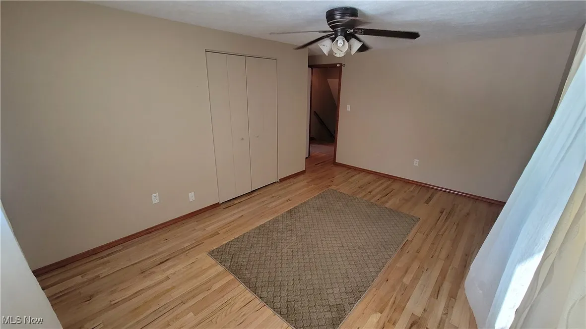Unfurnished bedroom with light wood-type flooring, a closet, a ceiling fan, and a textured ceiling