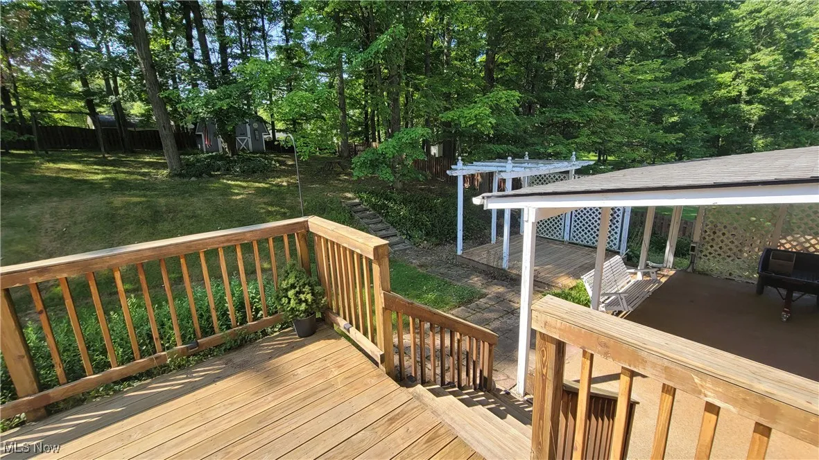 Wooden terrace featuring a lawn and view of wooded area