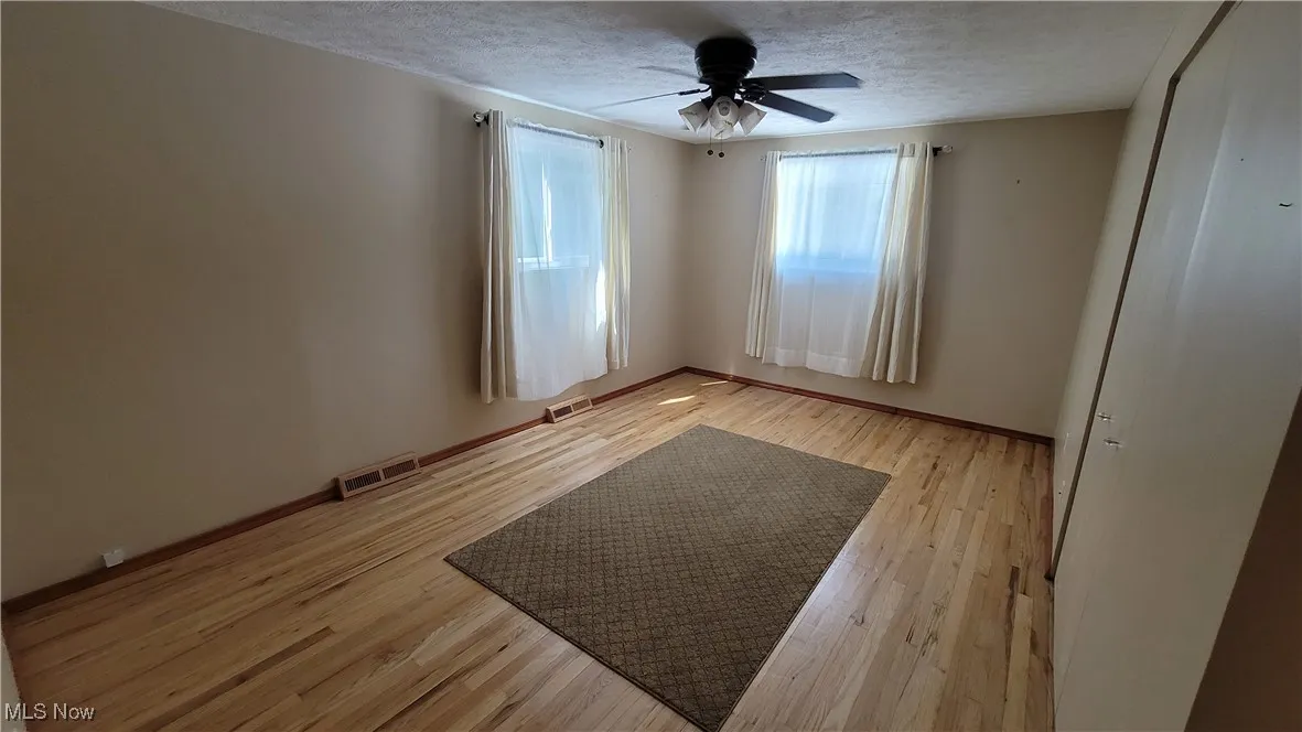 Spare room with light wood-style flooring, a ceiling fan, and a textured ceiling
