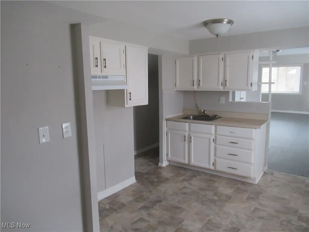 Kitchen featuring white cabinets, light countertops, and under cabinet range hood