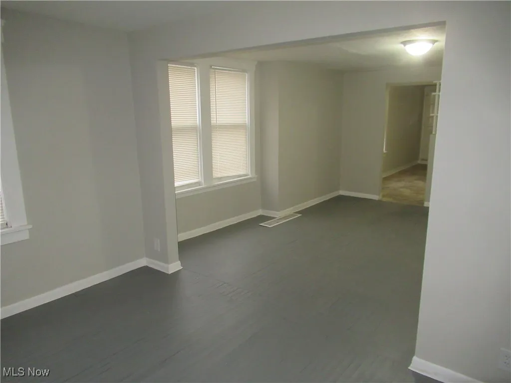 Spare room featuring baseboards and dark wood-type flooring