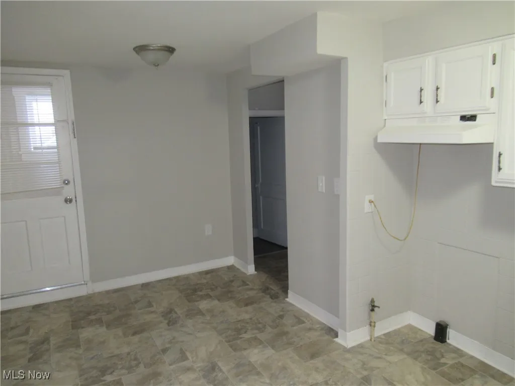 Laundry area featuring baseboards and stone finish floors