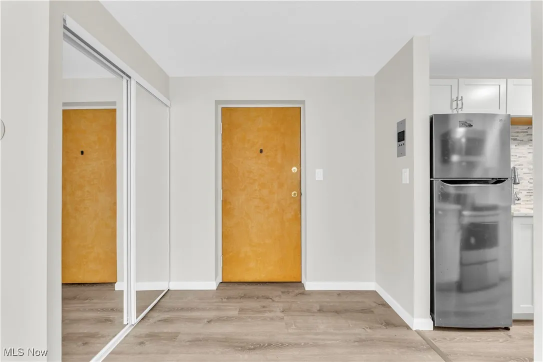 Kitchen with freestanding refrigerator, light wood-type flooring, and white cabinets
