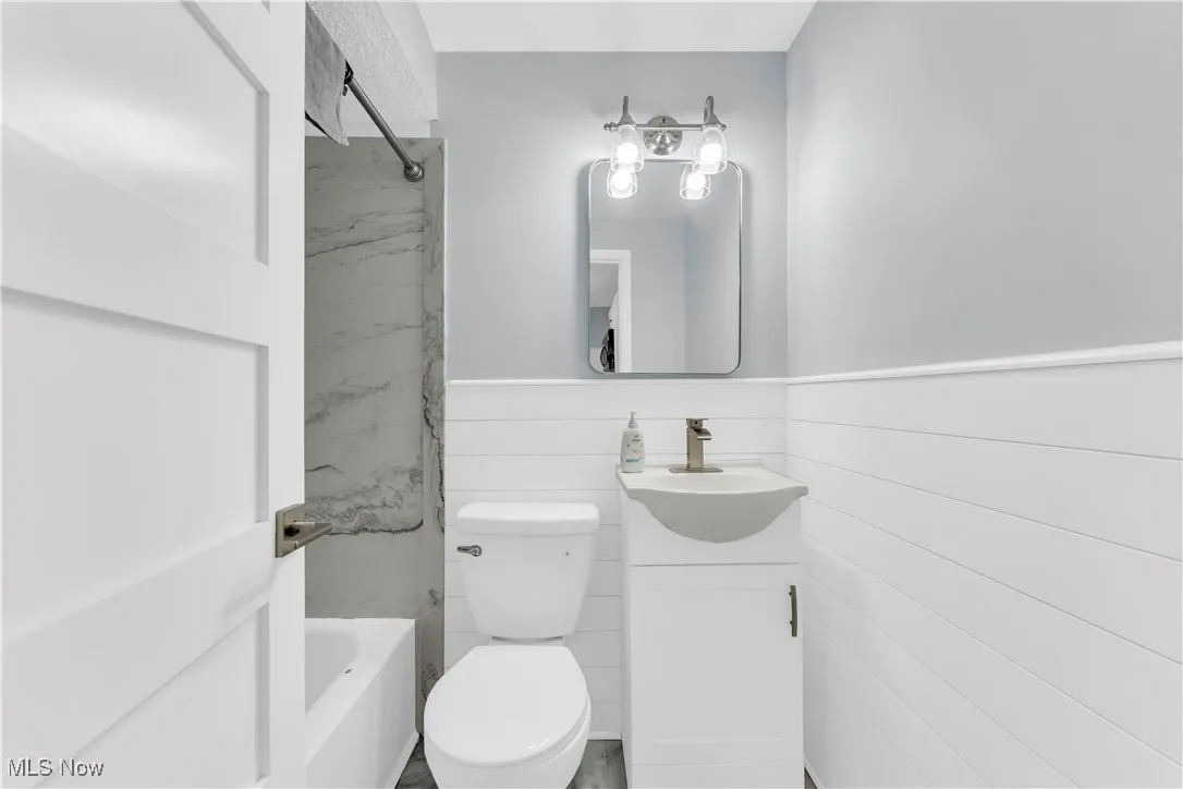 Bathroom featuring vanity, bathtub / shower combination, and wainscoting