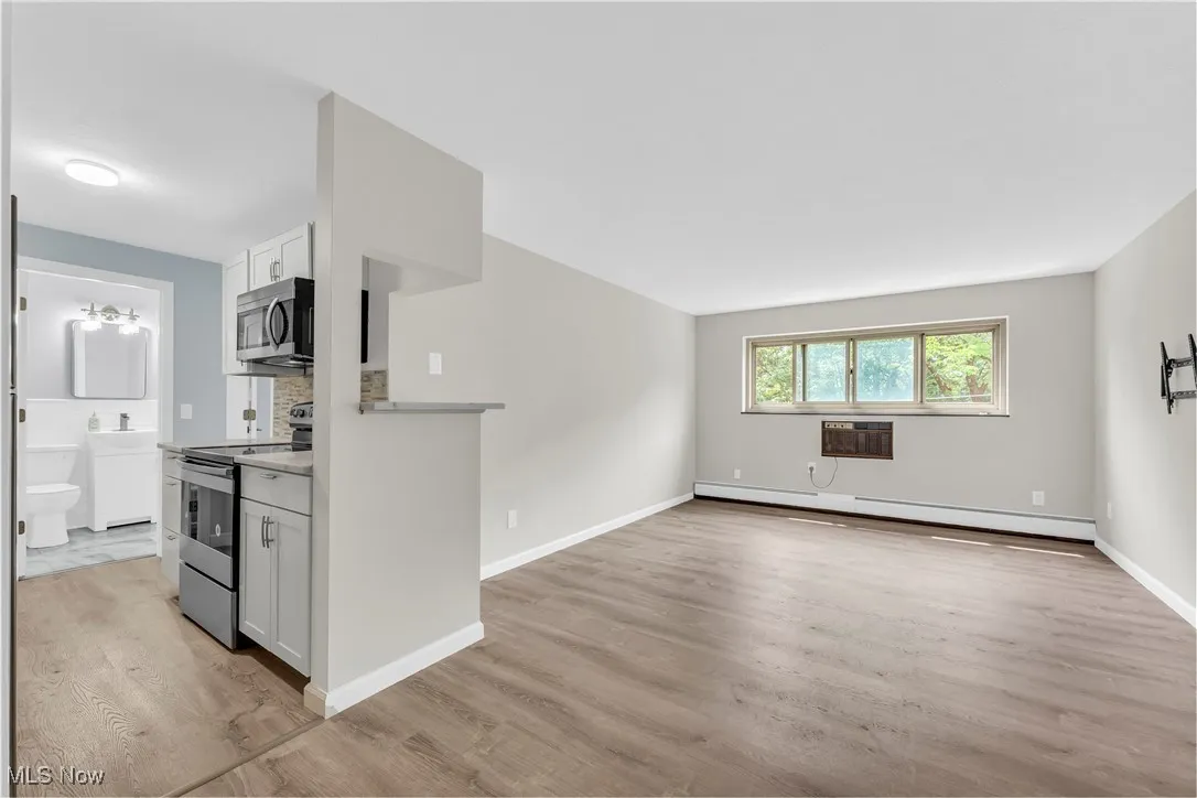 Unfurnished living room featuring light wood-type flooring and a baseboard heating unit