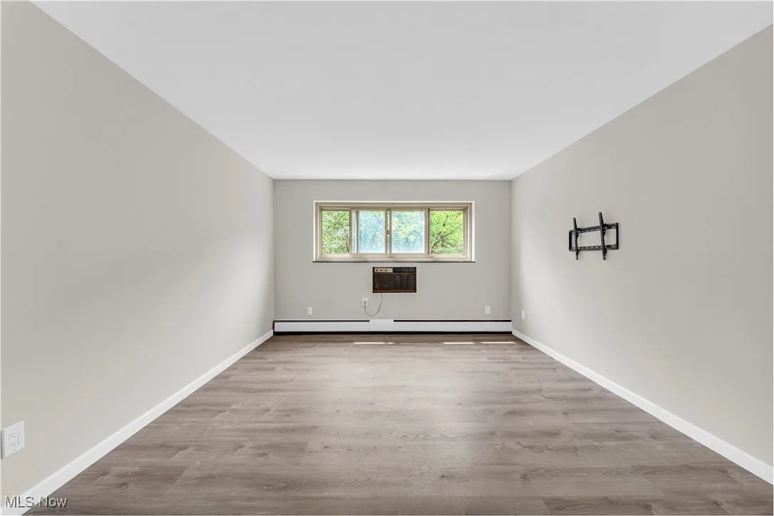 Empty room with light wood-style floors and a baseboard heating unit
