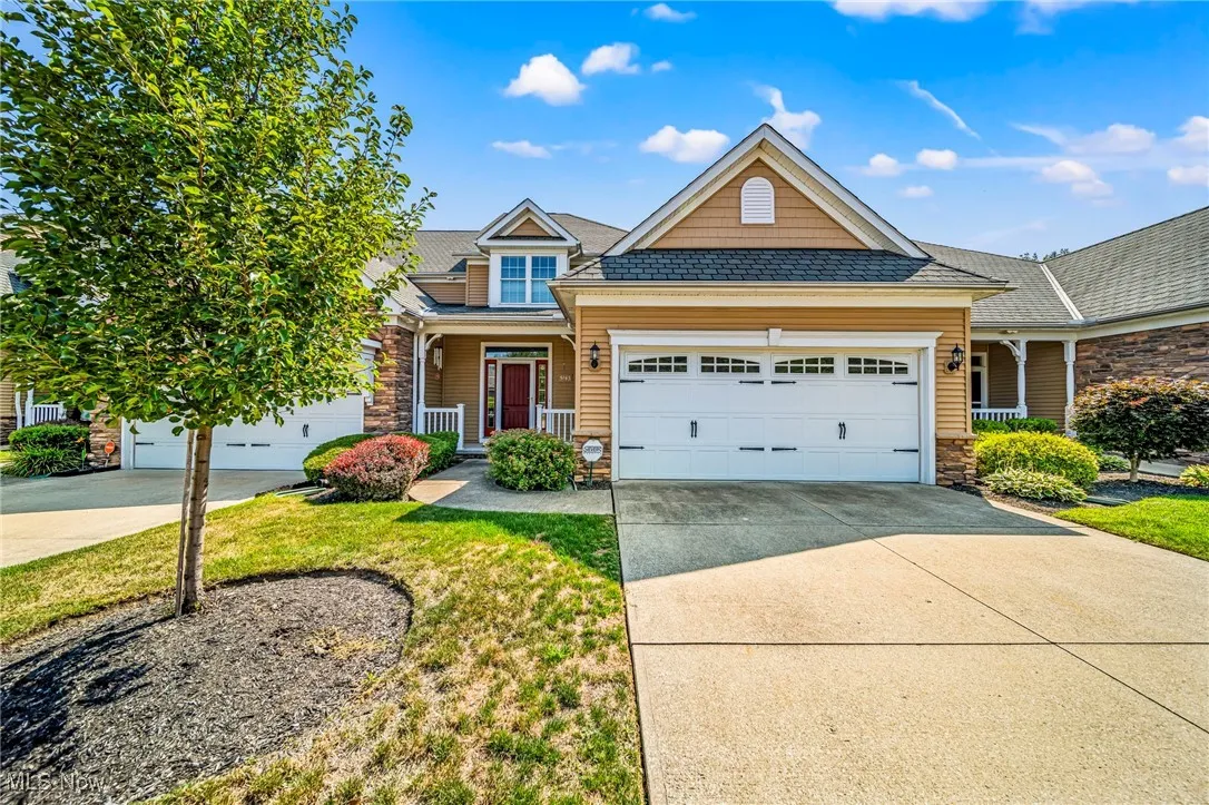 View of front of property with stone siding, a porch, concrete driveway, a front lawn, and an attached garage