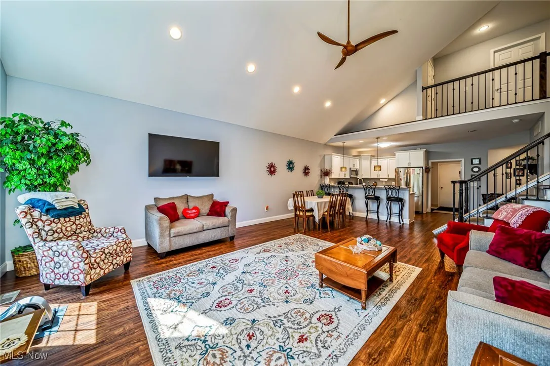 Living area with stairs, dark wood-style floors, high vaulted ceiling, a ceiling fan, and recessed lighting