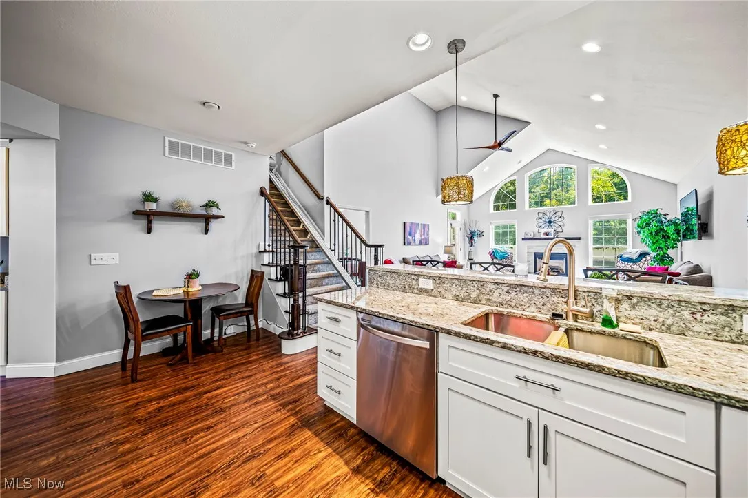 Kitchen featuring hanging light fixtures, light stone counters, stainless steel dishwasher, high vaulted ceiling, and recessed lighting