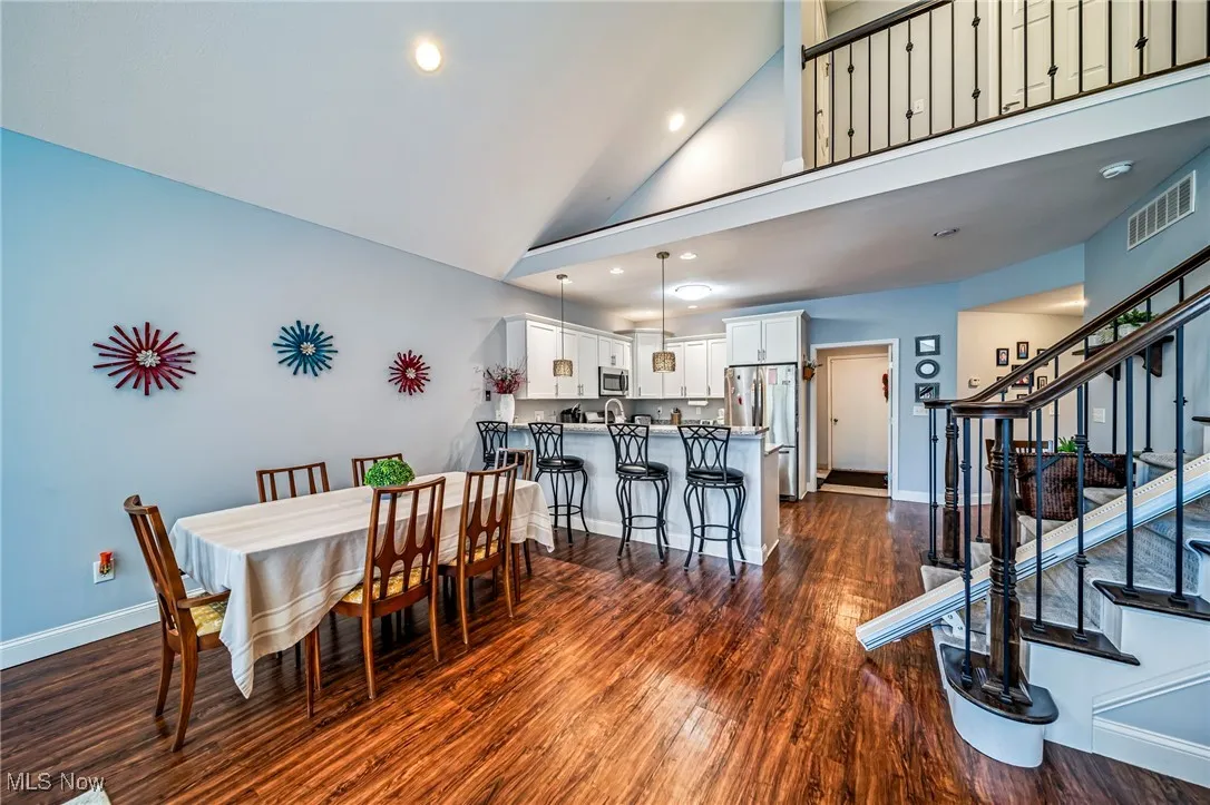 Dining space with dark wood finished floors, stairway, high vaulted ceiling, and recessed lighting