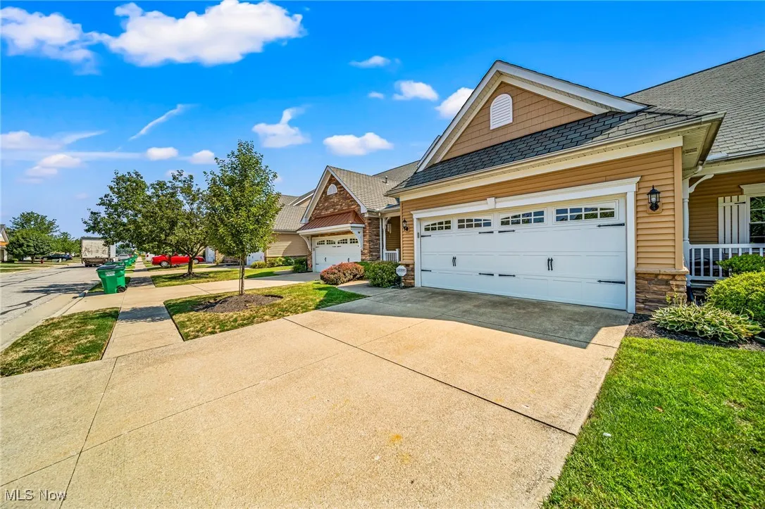 View of front of house with concrete driveway, stone siding, an attached garage, and roof with shingles