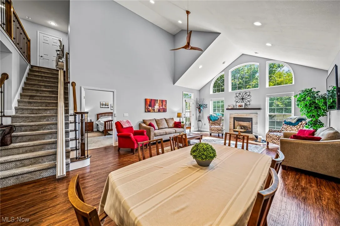 Dining room with high vaulted ceiling, a fireplace, dark wood-type flooring, recessed lighting, and stairs