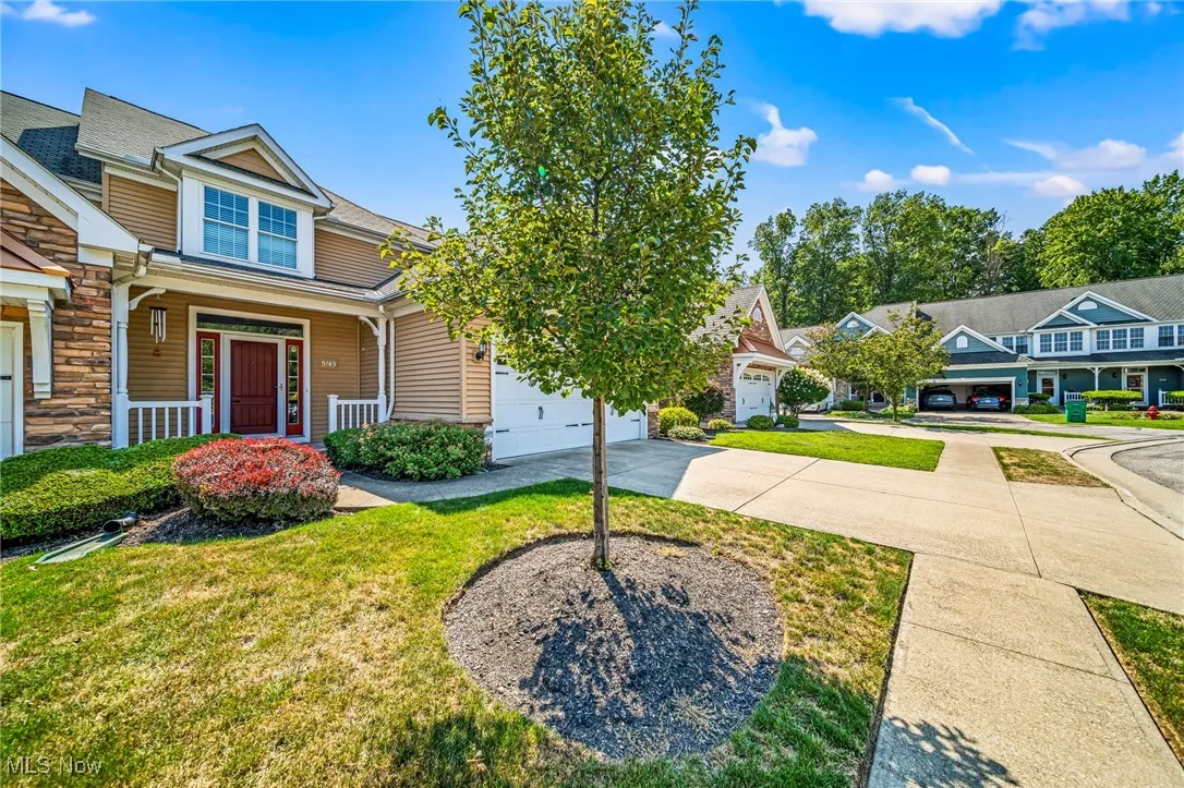 View of front of home featuring a porch, concrete driveway, stone siding, a front lawn, and a garage