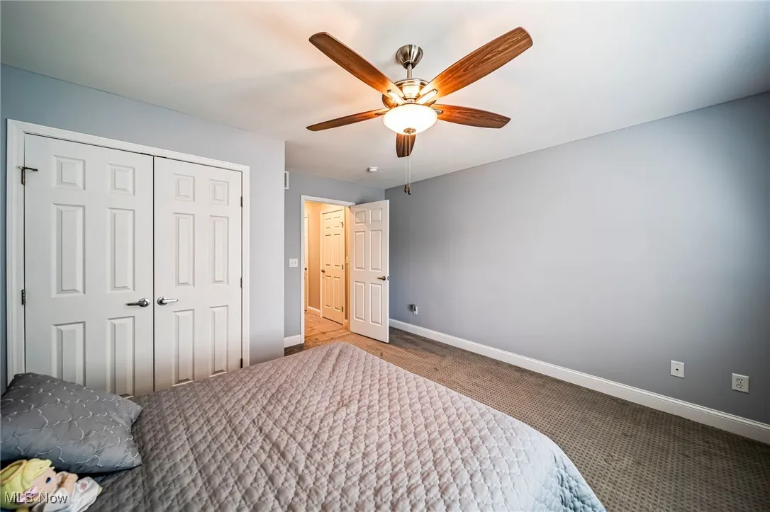 Carpeted bedroom featuring a closet and a ceiling fan