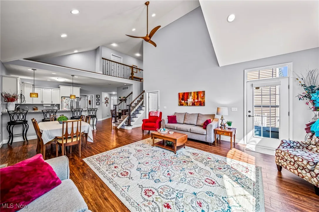 Living area with dark wood-style floors, stairs, high vaulted ceiling, recessed lighting, and a ceiling fan