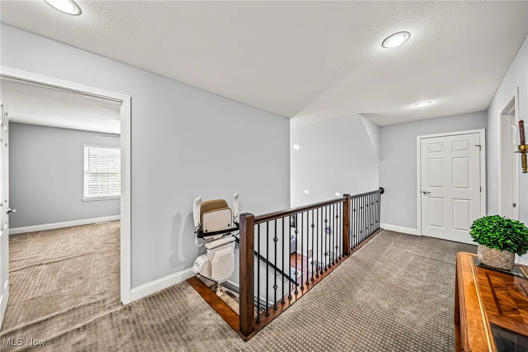 Hall featuring carpet floors, an upstairs landing, a textured ceiling, and recessed lighting