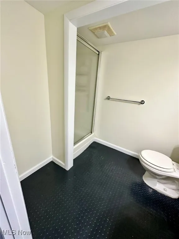 Full bath with a shower stall and baseboards