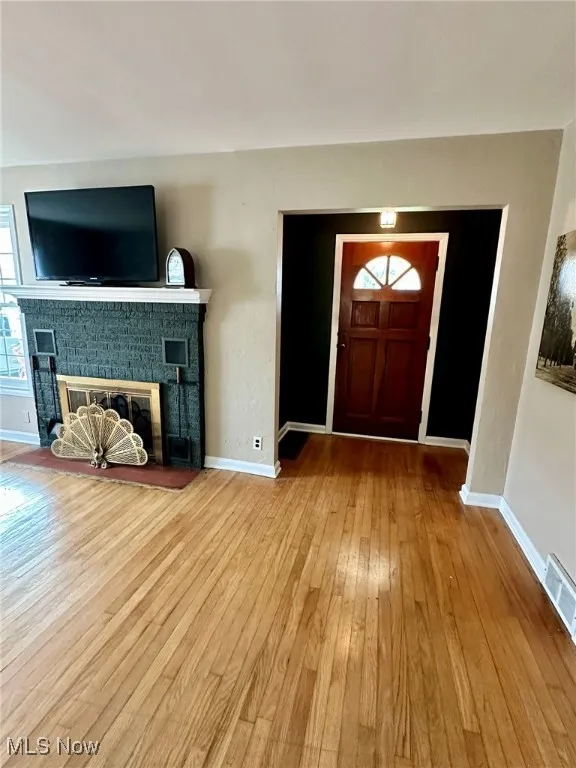 Foyer entrance with light wood-style flooring and a fireplace