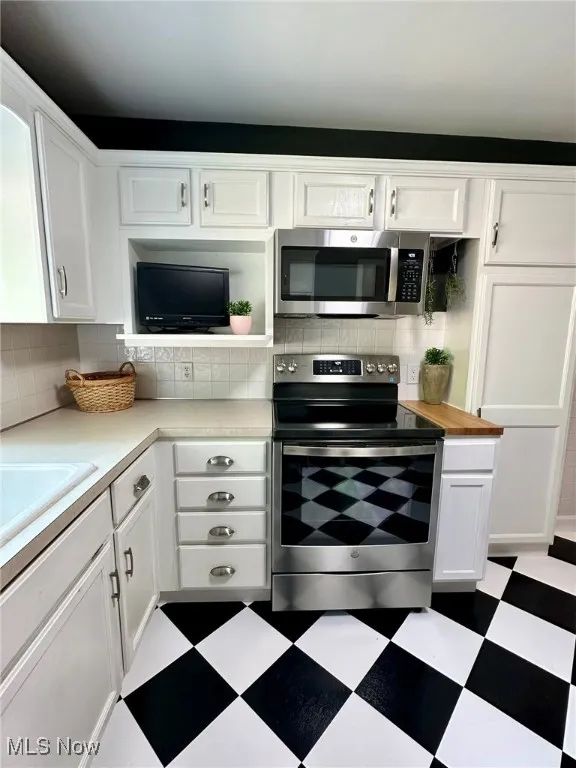 Kitchen with white cabinetry, appliances with stainless steel finishes, and light countertops