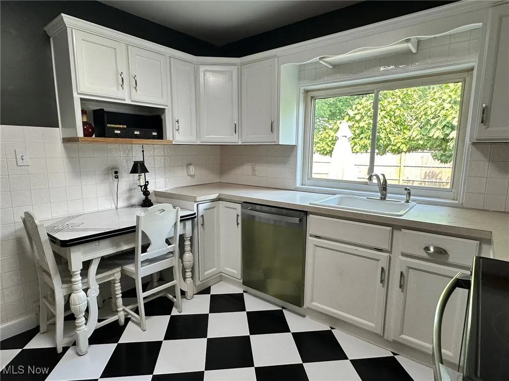 Kitchen with light floors, range, light countertops, and white cabinets