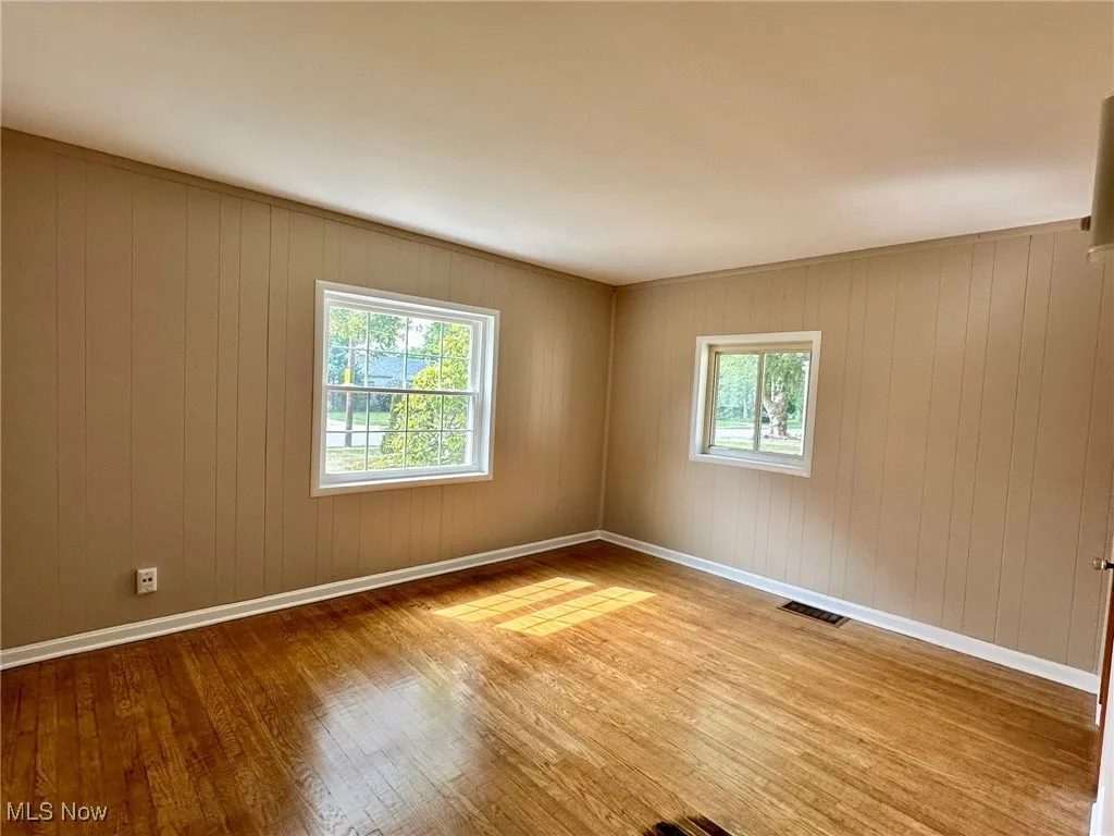 Spare room featuring hardwood / wood-style flooring and wood walls
