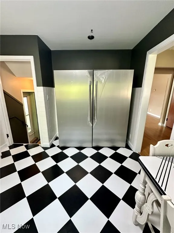 Kitchen featuring stainless steel refrigerator, wainscoting, and dark floors