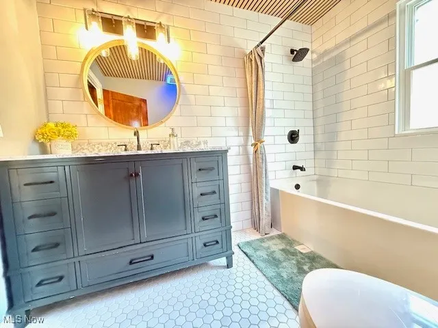 Bathroom with shower / tub combo with curtain, vanity, tile walls, and light tile patterned floors
