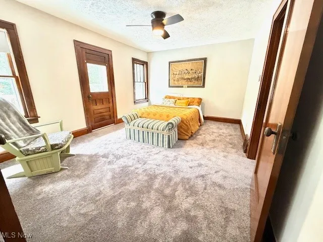 Bedroom with carpet, a textured ceiling, access to outside, and ceiling fan