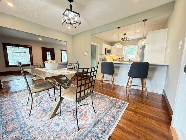 Dining room featuring dark wood-type flooring, a chandelier, recessed lighting, and a textured ceiling
