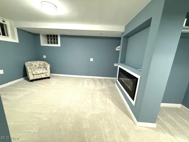 Unfurnished room featuring carpet flooring and a glass covered fireplace
