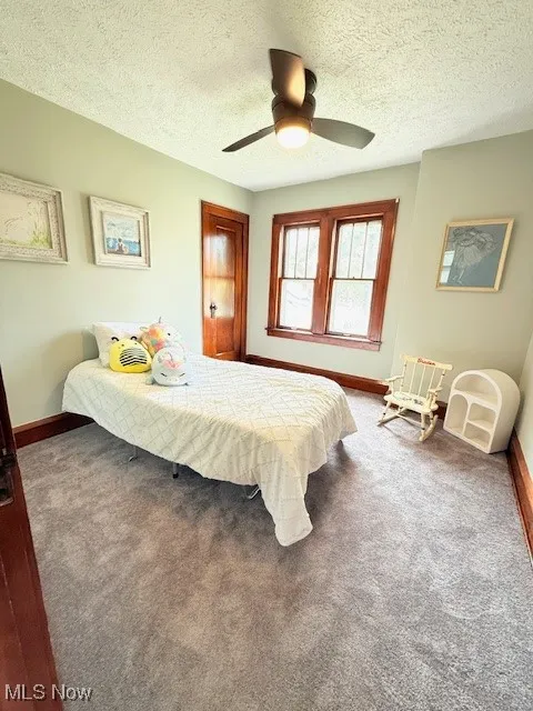 Carpeted bedroom featuring a textured ceiling and a ceiling fan