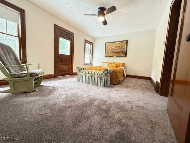 Carpeted bedroom with a textured ceiling, access to exterior, and a ceiling fan
