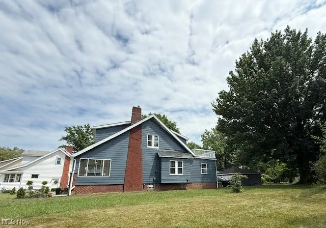 View of property exterior featuring a chimney and a lawn
