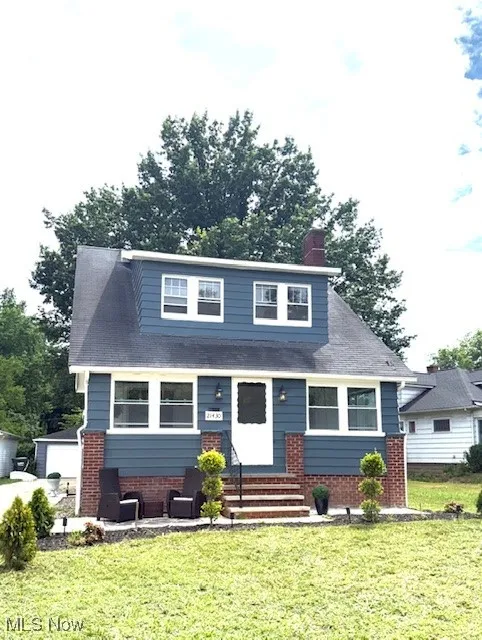 Bungalow-style house with a front yard, brick siding, and an outbuilding
