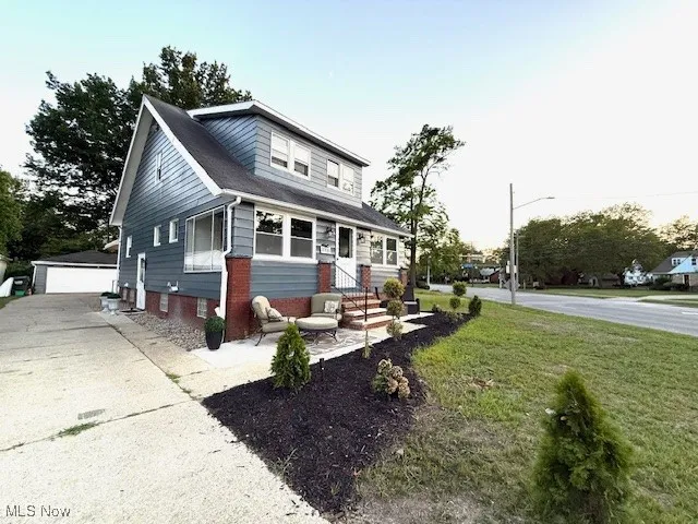 Bungalow-style house featuring an outdoor structure, a front lawn, a detached garage, and brick siding