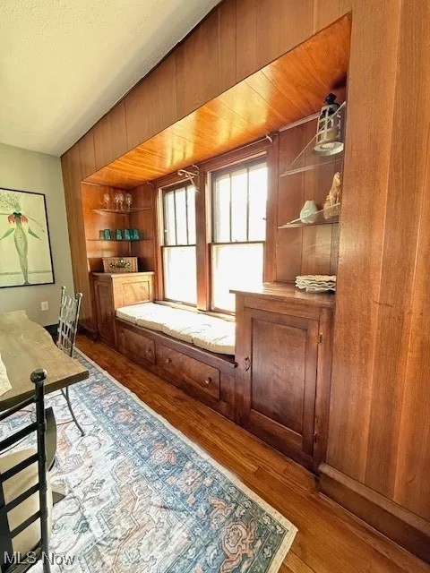 Home office with wooden walls, dark wood finished floors, and a textured ceiling