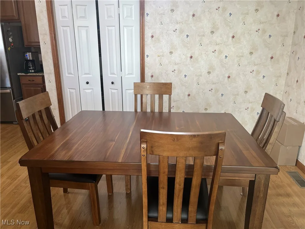 Dining space with wallpapered walls and light wood-type flooring