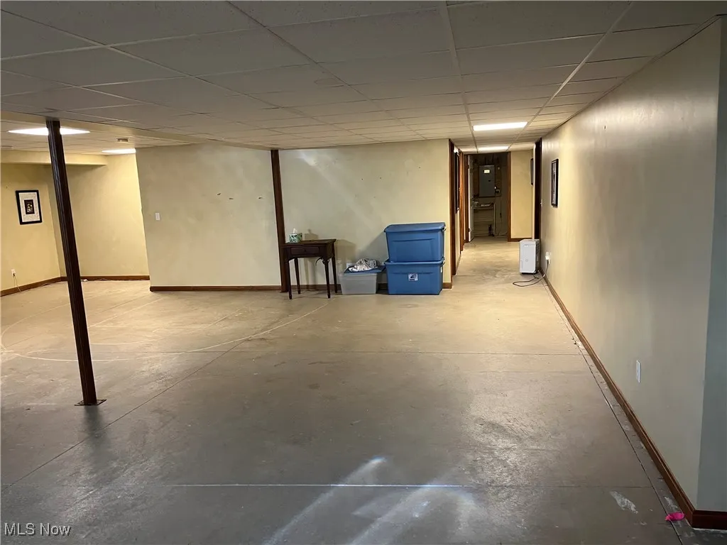 Finished basement with a paneled ceiling and baseboards