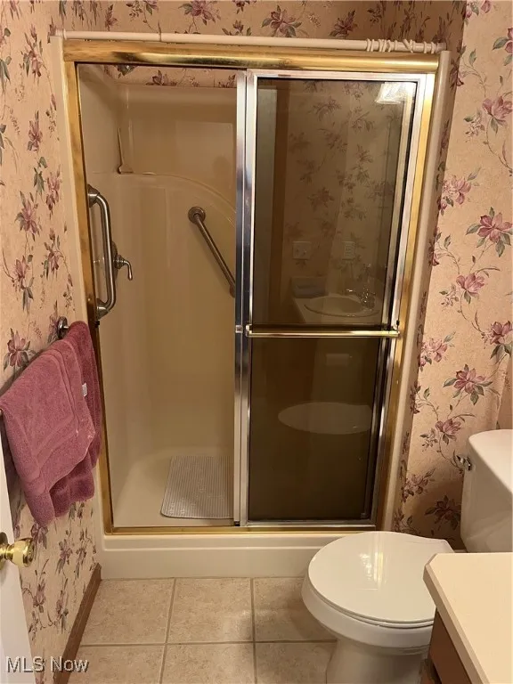 Bathroom featuring wallpapered walls, vanity, a stall shower, and tile patterned flooring
