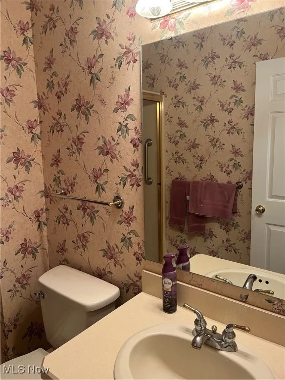 Bathroom featuring wallpapered walls and vanity