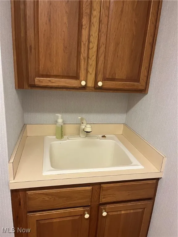 Laundry area with a sink and wallpapered walls