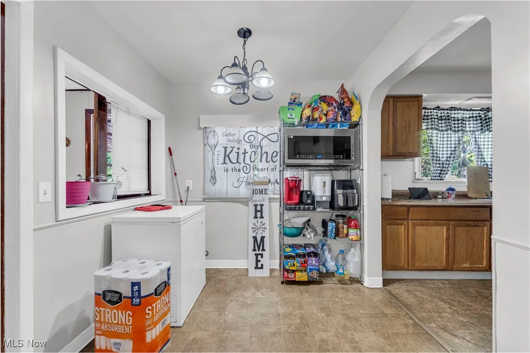 Kitchen with brown cabinetry, white fridge, a chandelier, and stainless steel microwave