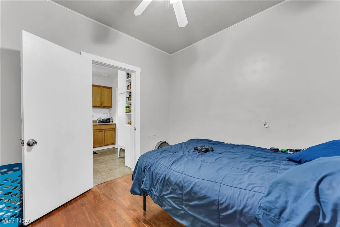 Bedroom featuring wood finished floors, crown molding, and ceiling fan