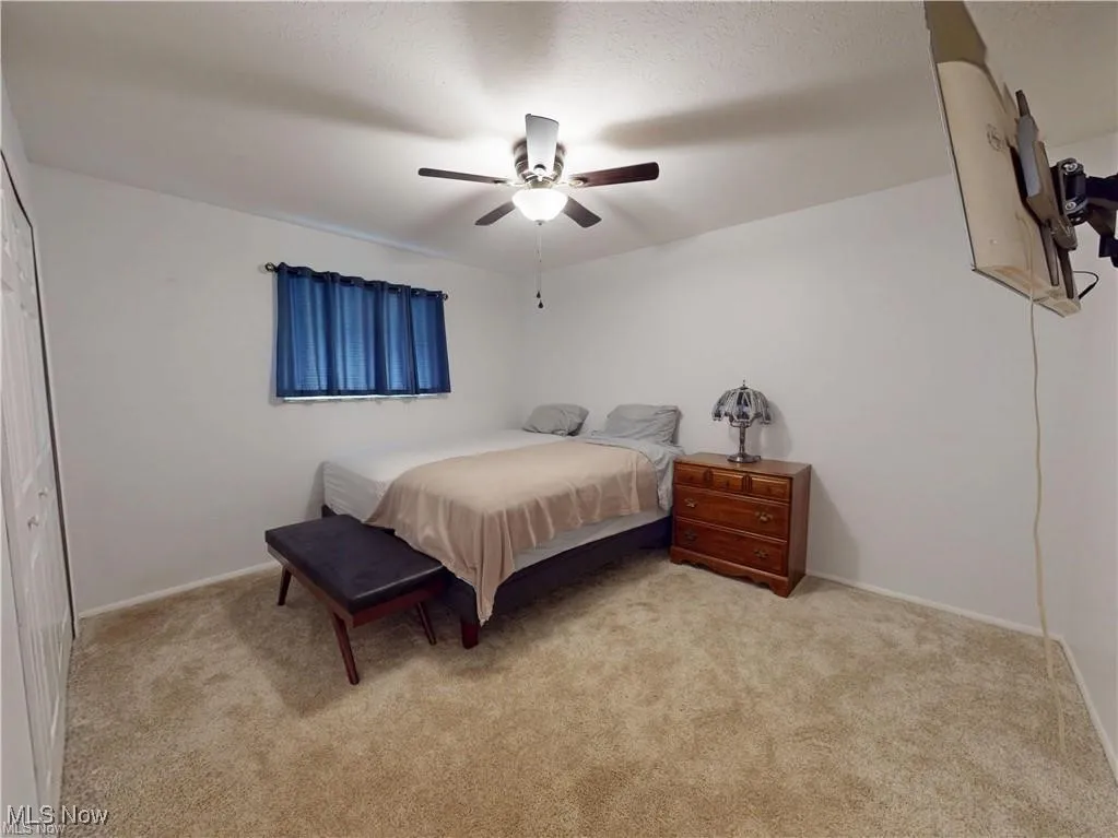 Bedroom with light colored carpet, a closet, and a ceiling fan
