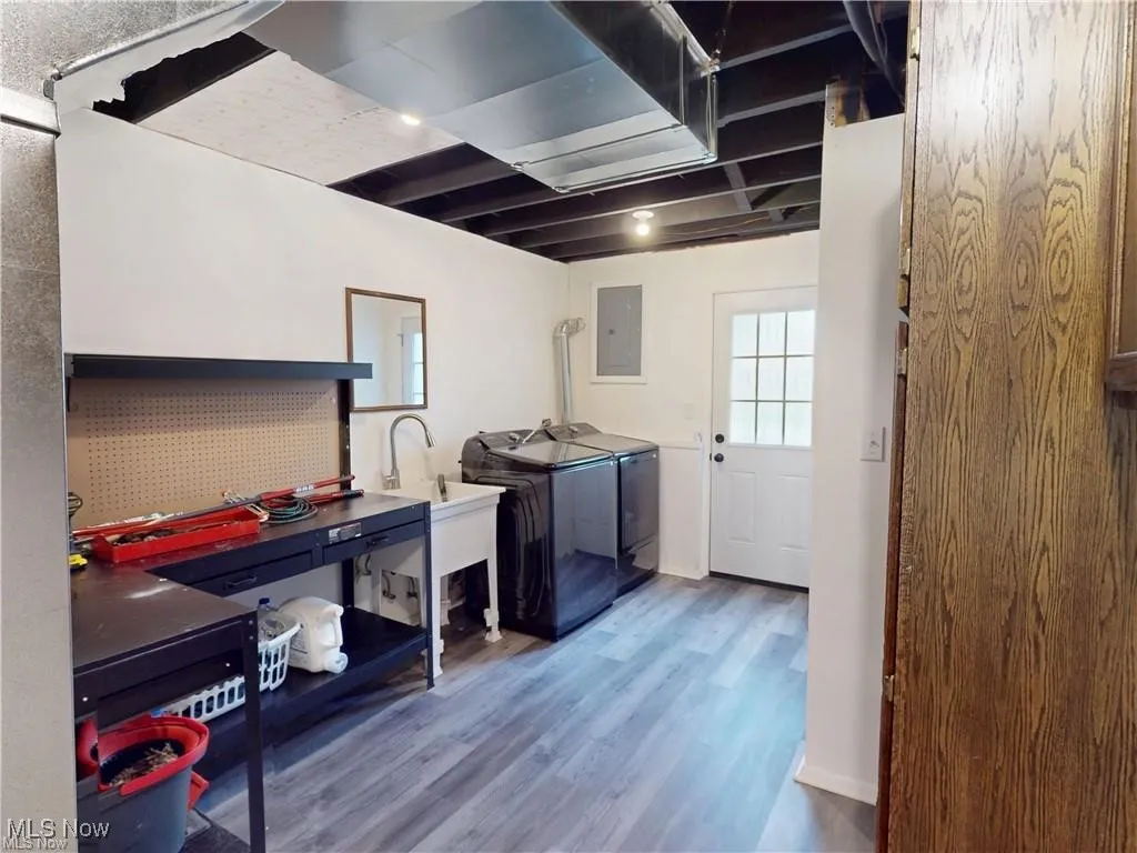 Laundry area with wood finished floors, washer and dryer, and electric panel