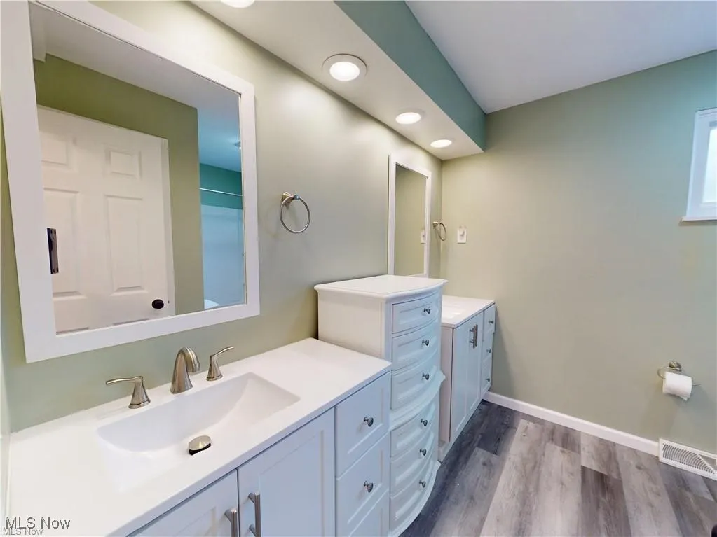 Full bath with light wood-style flooring, two vanities, and recessed lighting