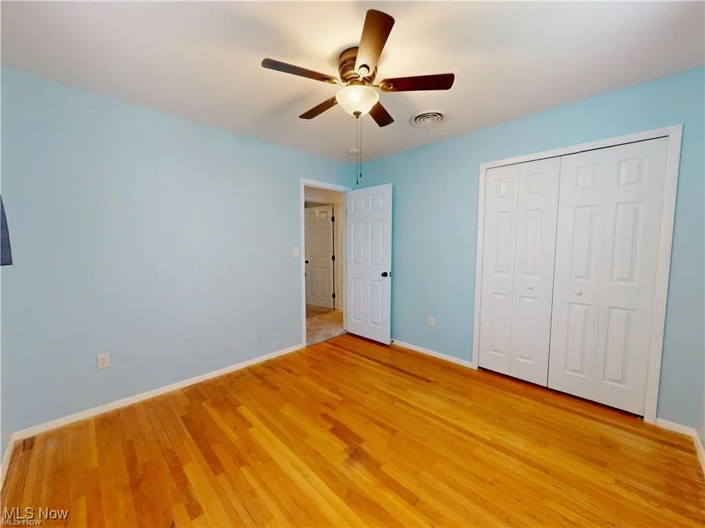 Unfurnished bedroom with light wood-type flooring, a ceiling fan, and a closet