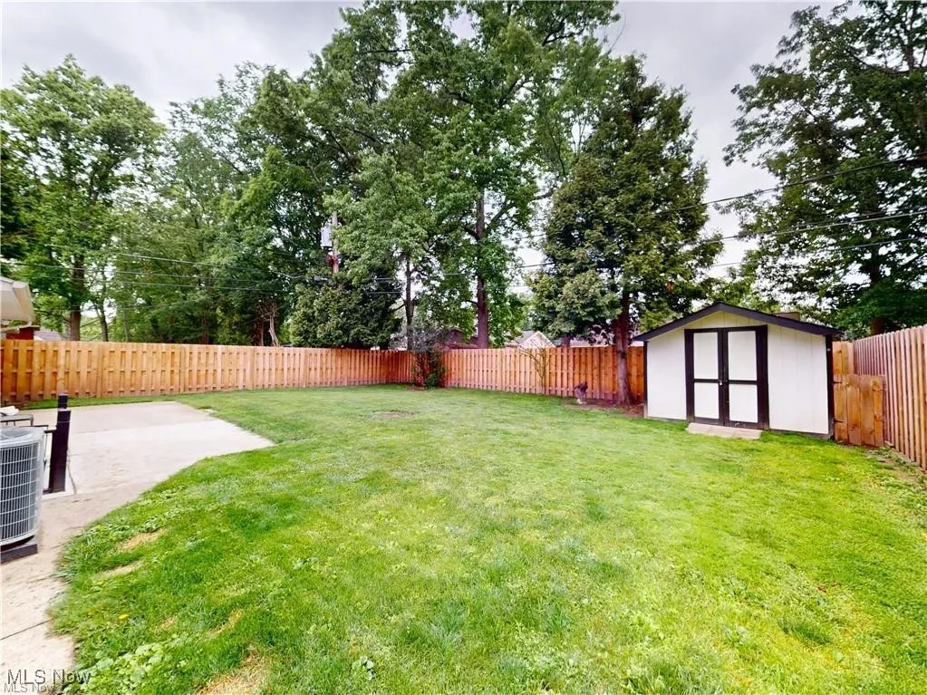 Fenced backyard featuring a storage shed and a patio area