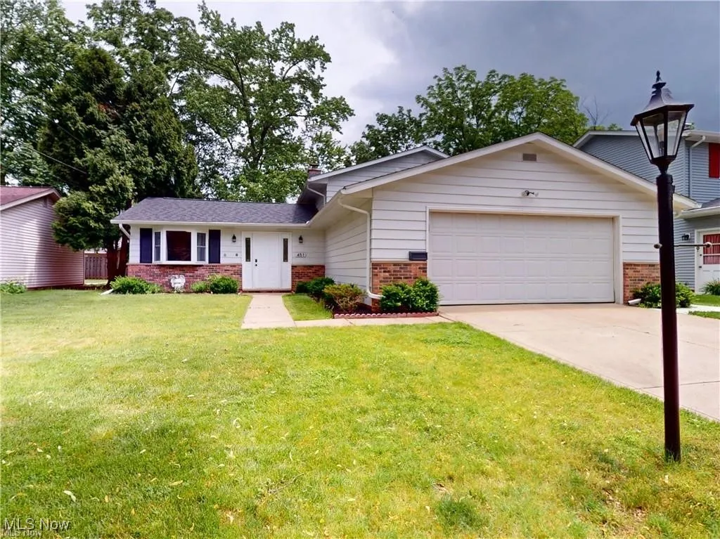 View of front of house with brick siding, driveway, an attached garage, and a front lawn